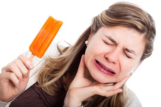 Woman with sensitive teeth eating cold Popsicle